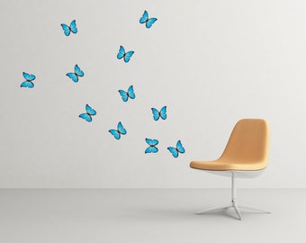 May include: A light brown chair with a white base sits in a room with a white wall. Blue butterfly decals are scattered on the wall.