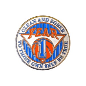 May include: A round, silver-coloured coin with a blue and white striped background. The coin has a white triangle with the words "Year 1" and a basketball with the number "1" inside. The words "Clean and Sober" are at the top of the coin, and "To Thine Own Self Be True" are at the bottom.