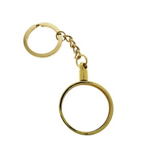 May include: A gold-colored key chain with a round ring and a smaller round ring attached to a chain. The smaller ring is designed to hold a coin.