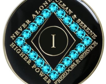May include: Black and gold coin with a turquoise blue diamond shape with the number 1 in the center. The words "Never Alone Clean & Serene Higher Power Freedom & Service" surround the diamond.