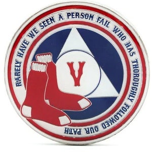 May include: A round, silver coin with a red, white and blue design. The centre of the coin features a red "V" and a pair of red and white socks. The outer ring of the coin has the text "Rarely have we seen a person fail who has thoroughly followed our path" in a white circle on a blue background.