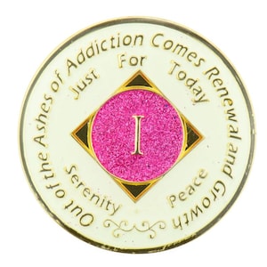 以下が含まれることがあります： 「Out of the Ashes of Addiction Comes Renewal and Growth Just For Today」という文字と、中央にピンク色の円の中に「1」という数字が書かれた、白と金の丸いトークン。円の真下に「Serenity」と「Peace」と書かれている。