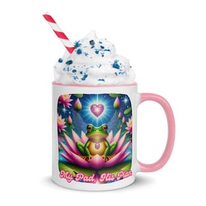 May include: White ceramic mug with a pink rim and handle. The mug features a colorful illustration of a green frog sitting on a pink lotus flower with a pink heart and blue wings. The text "My Pad, His Plan" is printed on the mug.