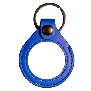 May include: A blue leather keychain holder with a bronze-colored rivet and a silver key ring. The holder has a circular opening and is stitched with white thread. The design is simple and functional.