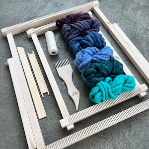 May include: A wooden loom with a set of colorful yarn for weaving. The loom is made of natural wood and has a simple design. The yarn is a variety of colors, including purple, blue, green, and teal.