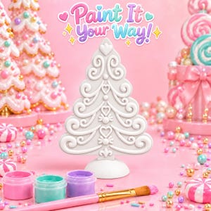 May include: A white, unpainted Christmas tree figurine with embossed scroll and heart details, standing on a circular base. Above it, the text reads Paint It Your Way! with small heart and star icons. Includes three paint pots and a brush.