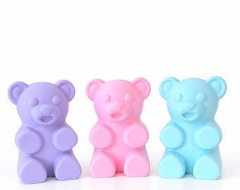 May include: Three bear-shaped figurines in a smooth, matte finish. The bear on the left is lavender, the center bear is light pink, and the bear on the right is light blue. Each bear features rounded ears, a snout, and a small open mouth.