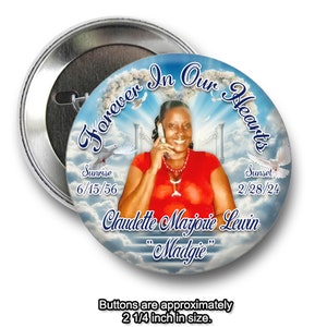 May include: A 2 1/4 inch button with a photo of a woman in a red shirt. The button has a blue background with white clouds and the text "Forever In Our Hearts". The text "Sunrise 6/15/56 Sunset 2/28/24 Claudette Marjorie Lewin "Madgie" is also on the button.