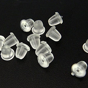 May include: A group of 14 clear plastic earring backs. The backs are small and round with a slight dome shape. They are designed to be used with stud earrings.