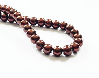 May include: A strand of brown pearl beads. The beads are round and smooth, and they are strung on a clear thread.