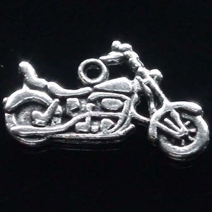 May include: A silver-colored motorcycle charm with intricate detailing. The charm features a classic motorcycle design, including wheels, a seat, and handlebars. The charm is designed to be attached to a necklace or bracelet.
