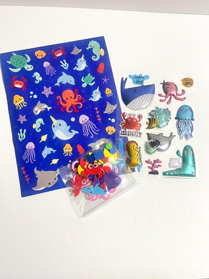 May include: A collection of ocean-themed stickers including a large blue sheet with various sea creatures, a clear sheet featuring 3D puffy stickers with text like "never stop" and "you can do it," and a small bag of colorful foam sea animal shapes.