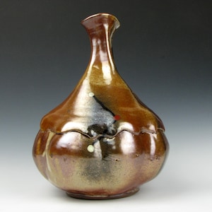 May include: A handmade ceramic jar with a lid. The jar is a mix of brown, black, and red hues, with a glossy finish. The jar has a bulbous body and a slender neck, and is likely used for storage.