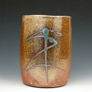 Puede incluir: Una taza de cerámica marrón con un diseño abstracto azul claro y rosa. La taza tiene un esmalte moteado y una forma redondeada.