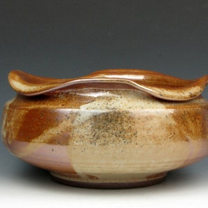 May include: A ceramic bowl with a brown and white glaze. The bowl has a unique, wavy rim.