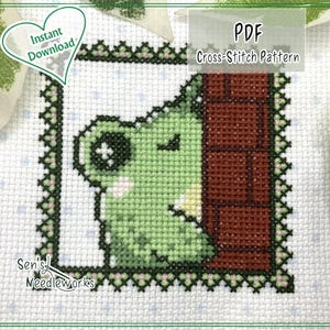 Könnte beinhalten: Kreuzstichmuster mit einem grünen Frosch, der hinter einer Backsteinmauer hervorlugt. Das Design ist mit einem dekorativen Rahmen versehen und enthält den Text "PDF Cross-Stitch Pattern" und "Instant Download". Das Design befindet sich auf weißem Hintergrund.