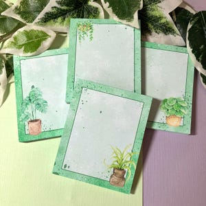 May include: Four green and white patterned sticky note pads with a watercolor design of potted plants. Each pad has a different plant design.