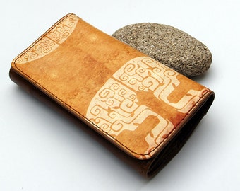 May include: A brown leather wallet with a white geometric pattern. The wallet is folded closed and has a stitched edge.