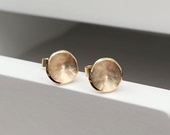 May include: A pair of gold-toned round stud earrings with a textured surface.