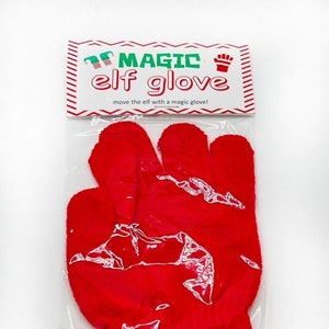 May include: Red knit elf glove in a clear plastic bag with a white label that reads "MAGIC elf glove" and "move the elf with a magic glove!"