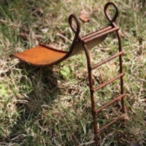 May include: A miniature rusty metal slide and ladder set for a fairy garden or miniature landscape. The slide is made of metal and has a rusty finish. The ladder has five rungs and is also made of metal.