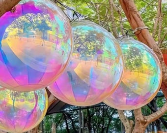 May include: Four iridescent, rainbow-colored, spherical orbs hanging from tree branches. The orbs are made of a clear material and reflect light, creating a colorful display.