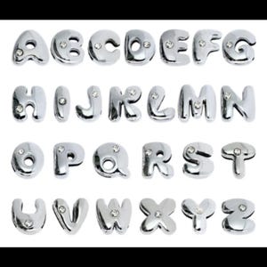 May include: Silver alphabet letter charms with rhinestones. Each letter is a separate charm. The letters are A through Z.