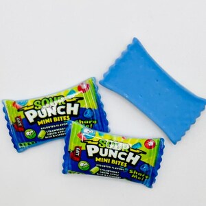 May include: Two blue and green Sour Punch Mini Bites candy packages with the text "Sour Punch Mini Bites" and "Share Me!" on the front. There is also a blue candy wrapper.