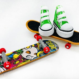 Puede incluir: Dos mini skateboards con zapatillas verdes y blancas en la parte superior. Una tabla de skate tiene una plataforma negra con un gráfico de una calavera y la otra tiene una plataforma negra con la palabra "T-Ride" impresa.
