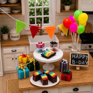Puede incluir: Una escena de fiesta de cumpleaños en miniatura con un soporte blanco para pasteles con pasteles de arcoíris y chocolate, cajas de regalo coloridas con lazos dorados, globos brillantes en un frasco, una pizarra con HAPPY B-DAY y banderines.