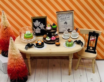 May include: A miniature Halloween-themed coffee shop with a sign that reads "Witches Brew Coffee House". The shop has a wooden table with a variety of miniature cakes and cupcakes decorated with Halloween themes. There are also two miniature coffee cups and a miniature guillotine.