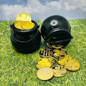 Può includere: Due pentole nere piene di monete d'oro con un quadrifoglio e il testo "Un quadrifoglio per la buona fortuna".
