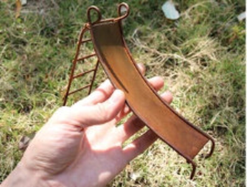 May include: A miniature rusty metal slide with a ladder, ideal for a fairy garden or miniature scene.