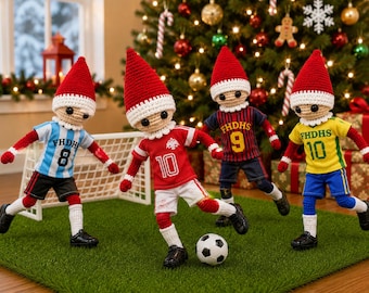 Puede incluir: Cuatro muñecos de ganchillo vestidos con uniformes de fútbol con gorros puntiagudos rojos y blancos. Cada muñeco lleva una camiseta con el texto FHDHS y un número, incluyendo 8, 10, 9 y 10. Están sobre una superficie verde con una portería y un balón.
