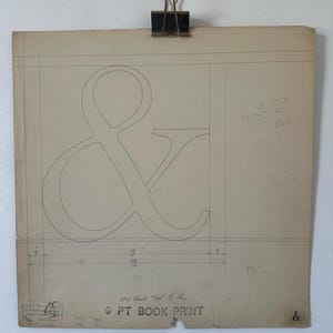 Pode incluir: Uma folha de papel vintage em tom off-white com um grande símbolo de e comercial desenhado à mão a lápis. O documento inclui linhas de layout técnicas, anotações numéricas manuscritas e o texto 100 Units Tool 18 Big 9 PT BOOK PRINT.