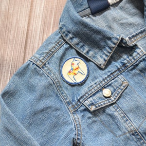 May include: A blue denim jacket with a yellow, red, and white embroidered patch of a horse on the left side of the jacket.