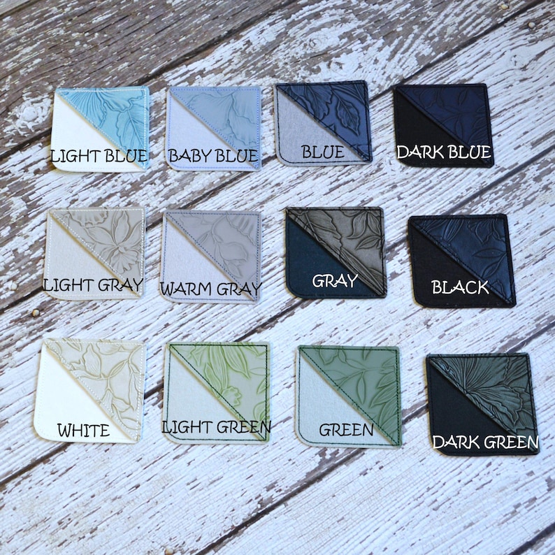 May include: Twelve fabric bookmark samples in various colors, including light blue, baby blue, blue, dark blue, light gray, warm gray, gray, black, white, light green, green, and dark green. Each bookmark has a floral design.