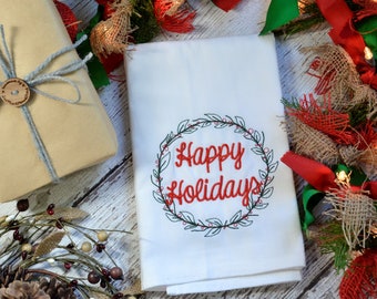 Puede incluir: Toalla de cocina blanca con bordado rojo de una corona verde con el texto "Happy Holidays" en su interior.
