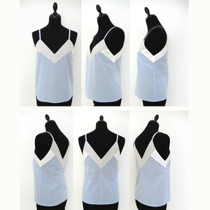 May include: A light blue sleeveless top with a white V-shaped neckline. The top is made of a lightweight fabric and has a relaxed fit.