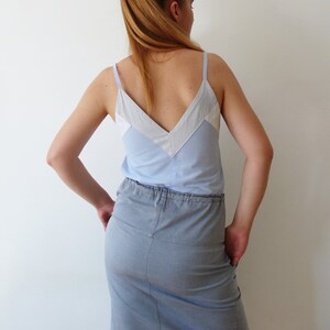 May include: A light blue sleeveless top with a white and light blue striped design. The top has a V-neckline and is paired with a light blue denim skirt.