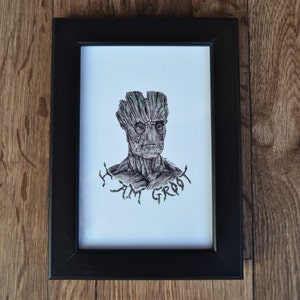May include: A black framed print of a drawing of Groot from Guardians of the Galaxy. The drawing is in black and white with green accents. The text "I am Groot" is written below the drawing.