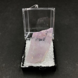 May include: A clear plastic display box with a white foam interior, containing a large, translucent, pale lavender crystal.