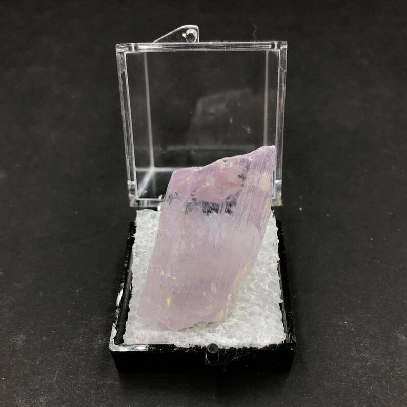 May include: A clear plastic display box with a white foam interior, containing a large, translucent, pale lavender crystal.