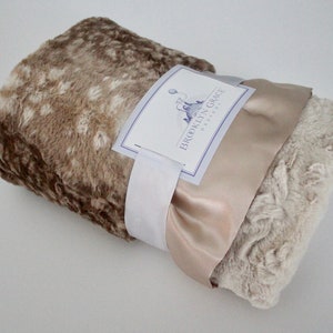 May include: A brown and beige faux fur throw blanket with a satin ribbon tied around it. The blanket is rolled up and the label "BROOKLYN GRACE DESIGNS" is visible.