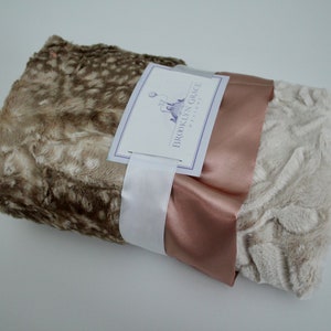 May include: A brown and white faux fur blanket with a rose gold satin ribbon and a white tag that reads "Brooklyn Grace Designs".