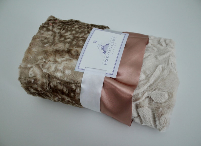 May include: A brown and white faux fur blanket with a rose gold satin ribbon and a white tag that reads "Brooklyn Grace Designs".