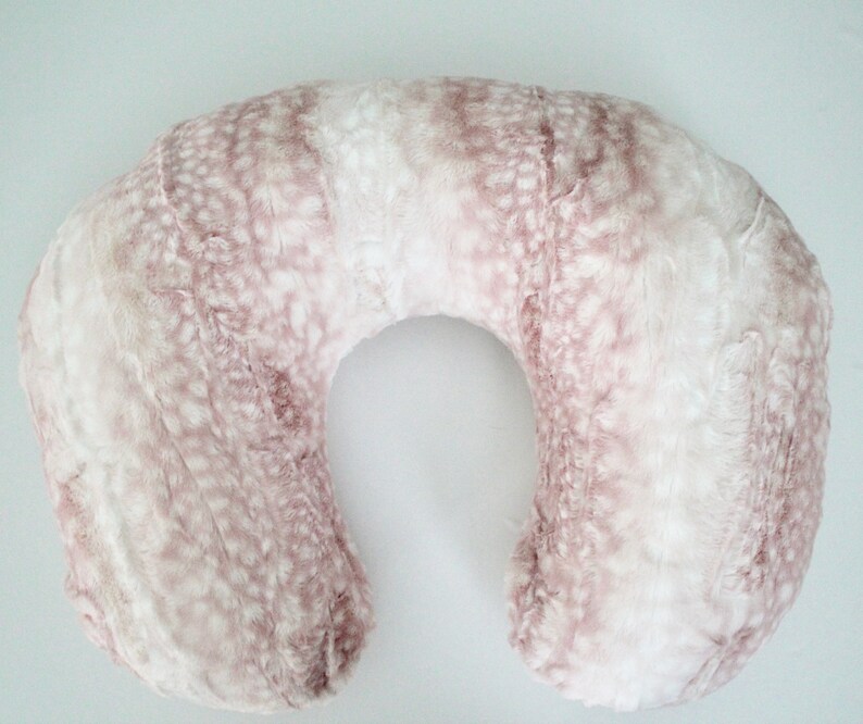 May include: A U-shaped pregnancy pillow with a soft, plush pink and white faux fur cover.