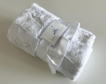 May include: A white faux fur baby blanket with a satin ribbon and a tag that reads "Brooklyn Grace Baby Boutique".