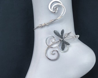 May include: Silver ankle bracelet with a dragonfly design. The bracelet is made of wire and has a delicate, whimsical look.
