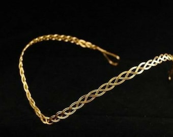 May include: A gold braided headband with a simple design. The headband is made of metal and has a delicate, feminine look.